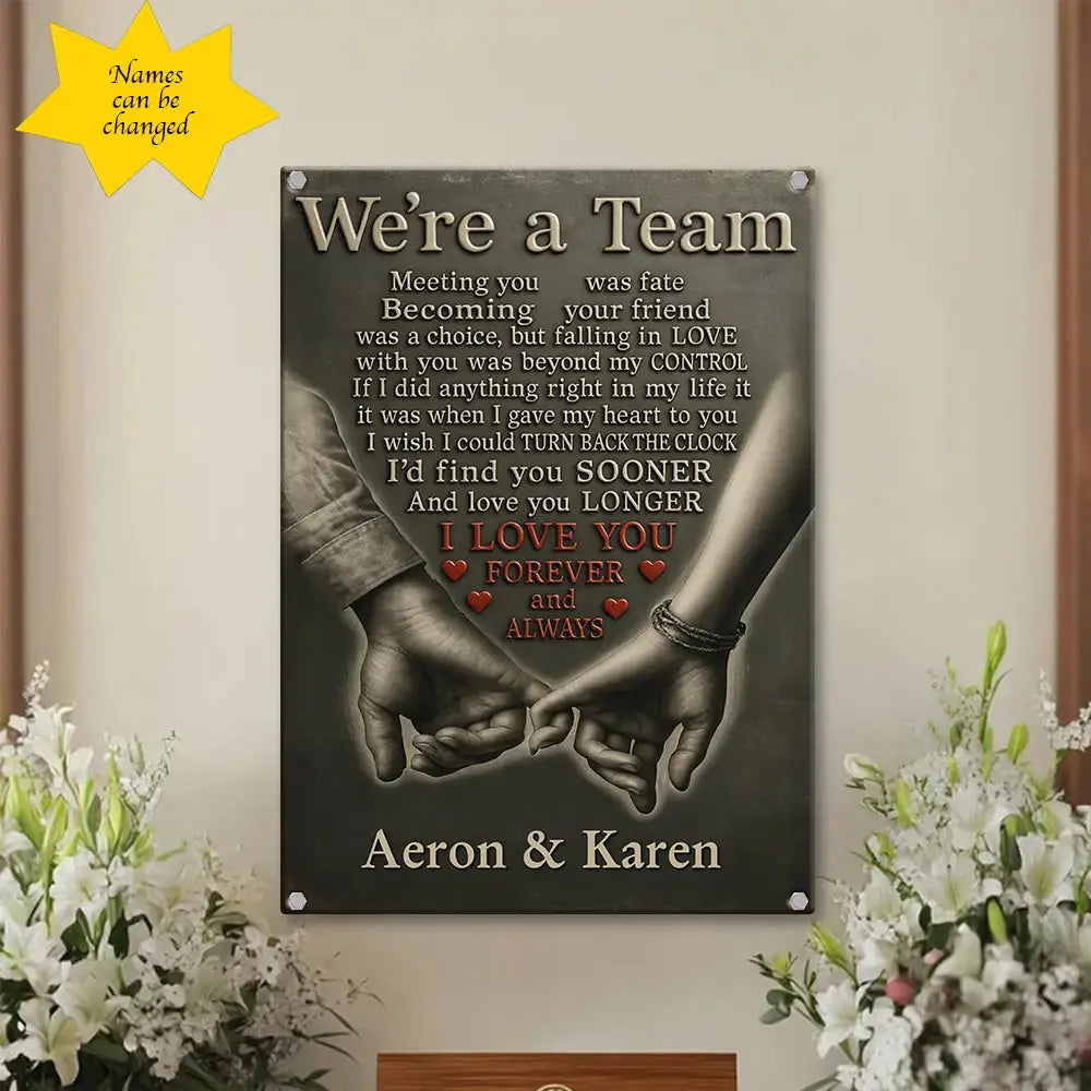 Decorative wall sign with hands holding text 'We're a Team' and personalized names 'Aeron & Karen' on a neutral background.